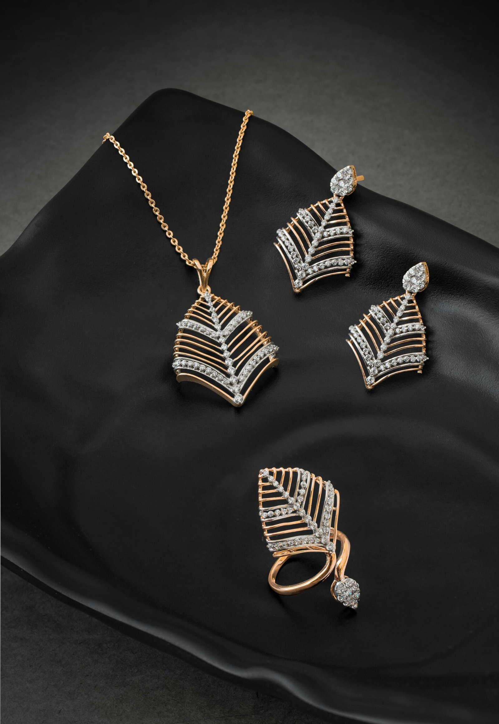 Elegant diamond necklace, earrings, and ring set displayed on a stylish black plate.